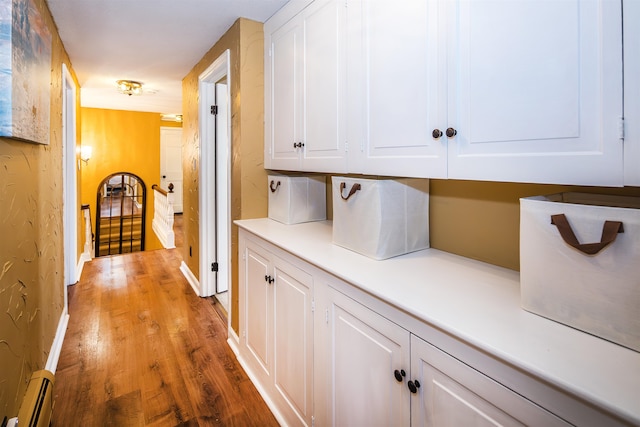 corridor with hardwood / wood-style flooring and a baseboard heating unit