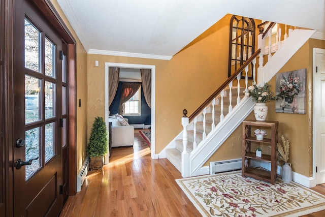 foyer entrance with light wood-type flooring, a baseboard radiator, and crown molding