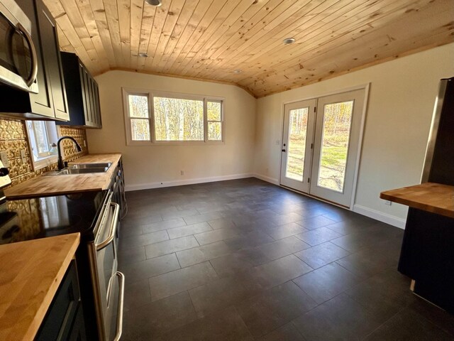 kitchen featuring butcher block countertops, vaulted ceiling, stainless steel appliances, and sink