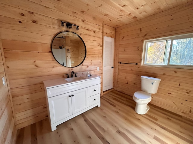 bathroom with hardwood / wood-style floors, toilet, wooden walls, vanity, and wood ceiling