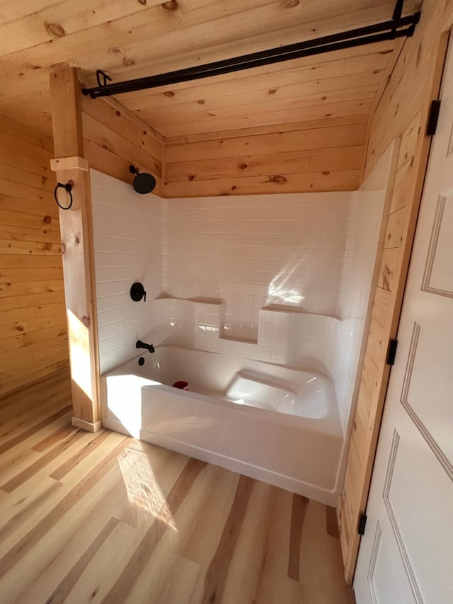 bathroom with wood ceiling, wood walls, wood-type flooring, and washtub / shower combination