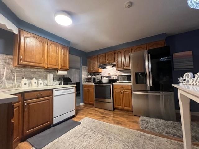 kitchen with decorative backsplash, light hardwood / wood-style flooring, and stainless steel appliances