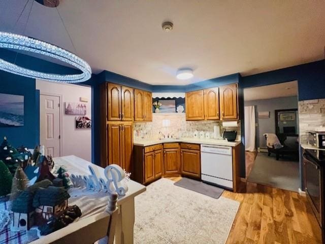 kitchen with decorative backsplash, white dishwasher, stainless steel range with electric stovetop, and light wood-type flooring