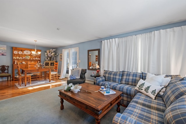 living room with hardwood / wood-style floors, baseboard heating, and an inviting chandelier