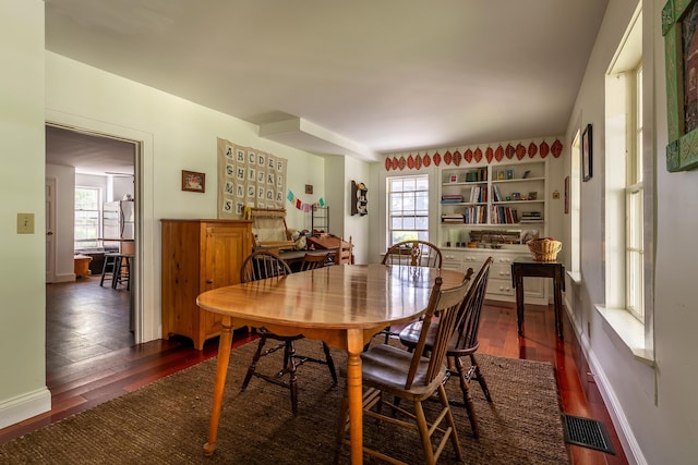 dining space featuring built in shelves and dark hardwood / wood-style flooring