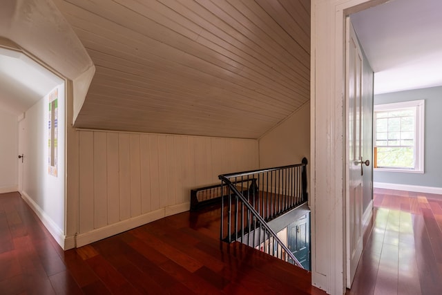 hall with dark hardwood / wood-style flooring, wooden ceiling, lofted ceiling, and wood walls