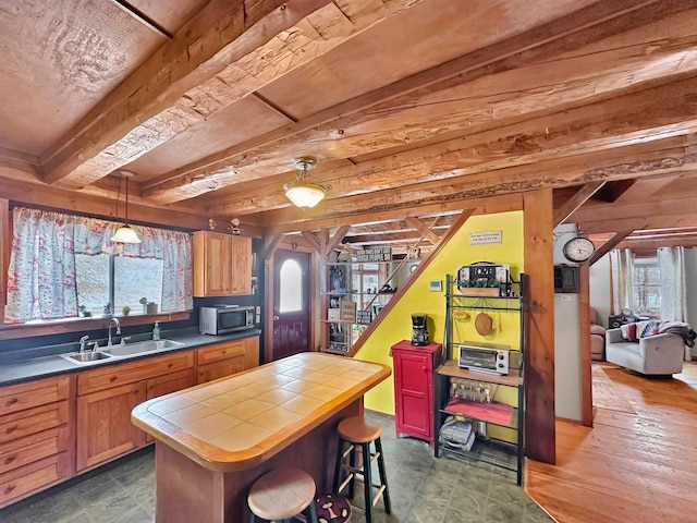 kitchen featuring a center island, sink, hanging light fixtures, tile counters, and dark hardwood / wood-style flooring