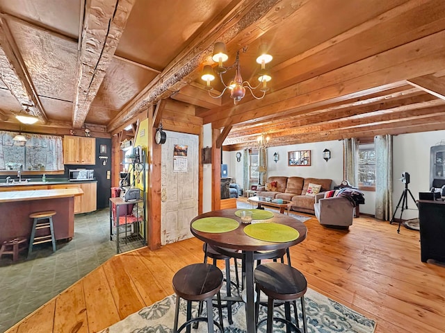 dining space with a chandelier, beam ceiling, hardwood / wood-style flooring, and sink