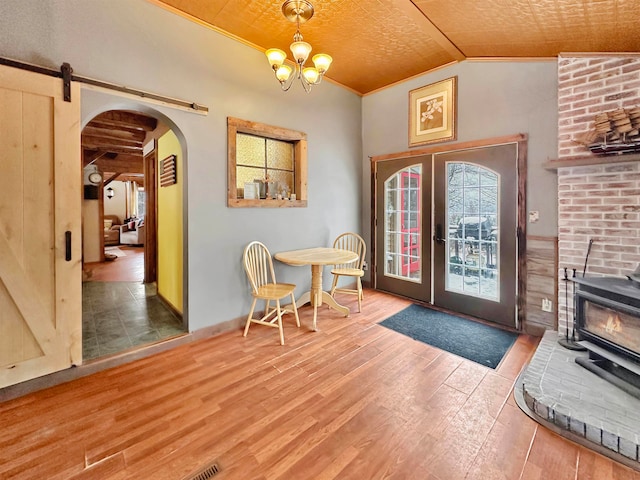 foyer with vaulted ceiling, crown molding, a barn door, hardwood / wood-style flooring, and a chandelier