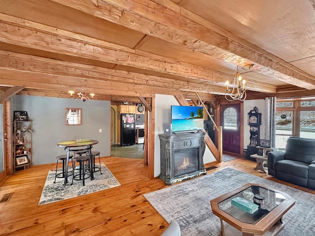 unfurnished living room with beam ceiling, wood-type flooring, and a notable chandelier