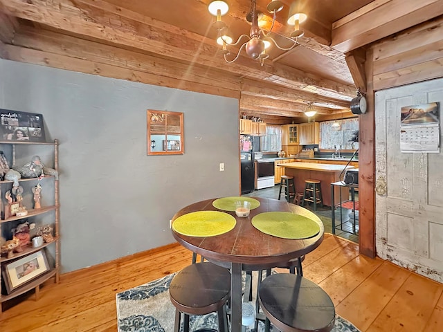 dining area with beamed ceiling, a notable chandelier, and light hardwood / wood-style flooring