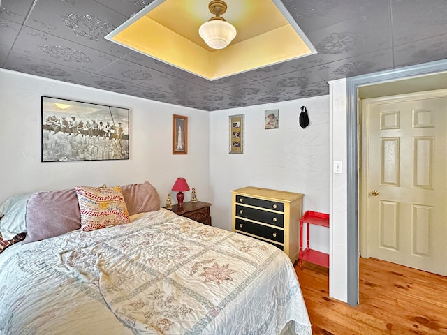 bedroom with hardwood / wood-style flooring and a tray ceiling