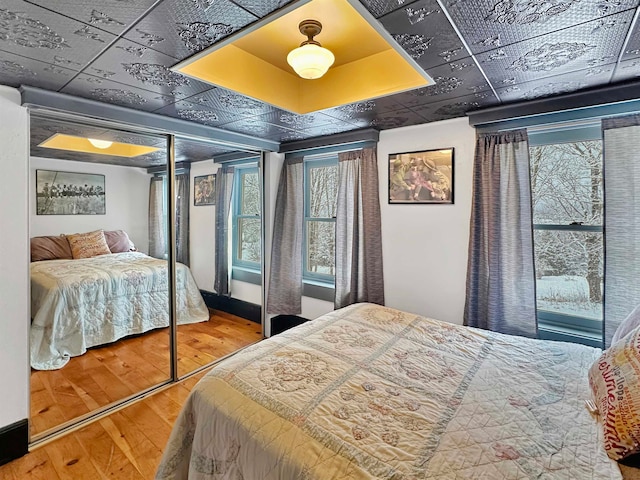 bedroom featuring a tray ceiling, a closet, and hardwood / wood-style flooring