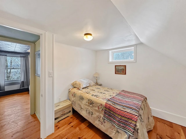 bedroom with light wood-type flooring and vaulted ceiling