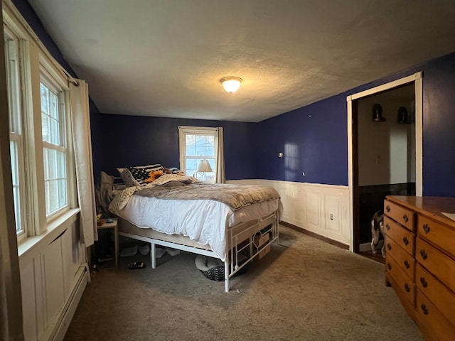 bedroom featuring dark carpet, a textured ceiling, and a baseboard heating unit