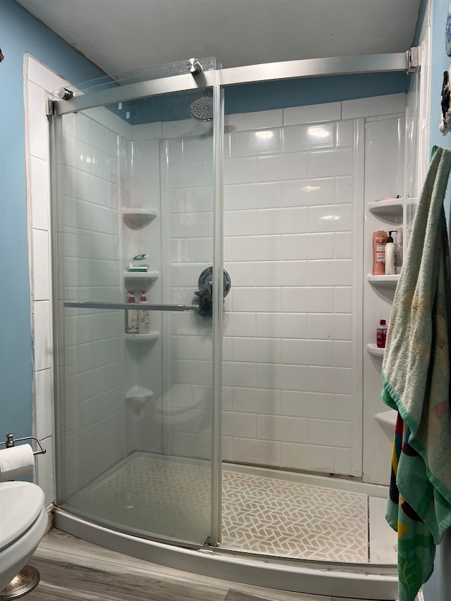 bathroom featuring toilet, an enclosed shower, and hardwood / wood-style flooring