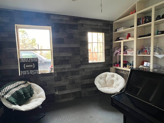 living area featuring carpet flooring, vaulted ceiling, and wooden walls