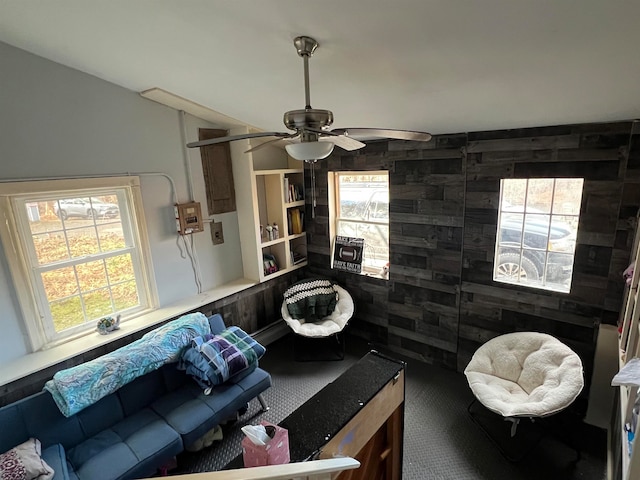 living room with ceiling fan, carpet floors, and wooden walls