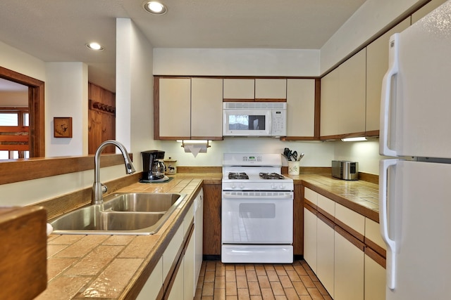 kitchen with white appliances, tile countertops, white cabinetry, and sink