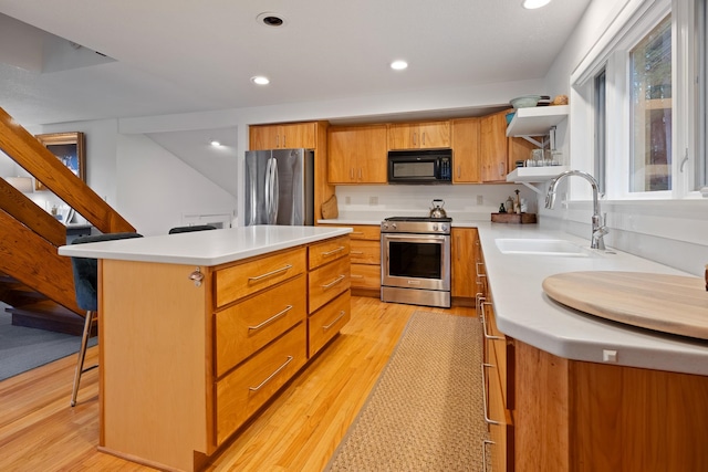 kitchen with a center island, a kitchen breakfast bar, sink, light hardwood / wood-style flooring, and appliances with stainless steel finishes