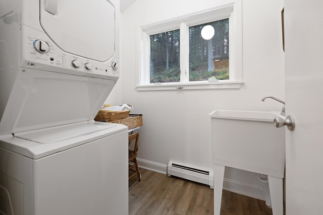 laundry room featuring a baseboard heating unit, dark hardwood / wood-style flooring, and stacked washer and clothes dryer