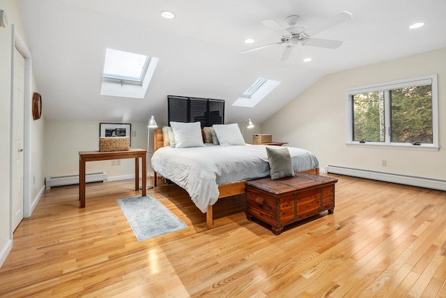 bedroom featuring vaulted ceiling with skylight, light hardwood / wood-style floors, and baseboard heating