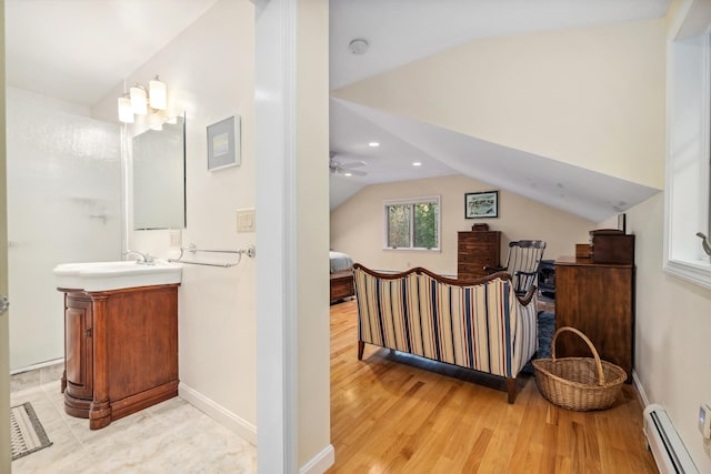 bathroom featuring vanity, vaulted ceiling, hardwood / wood-style flooring, ceiling fan, and baseboard heating