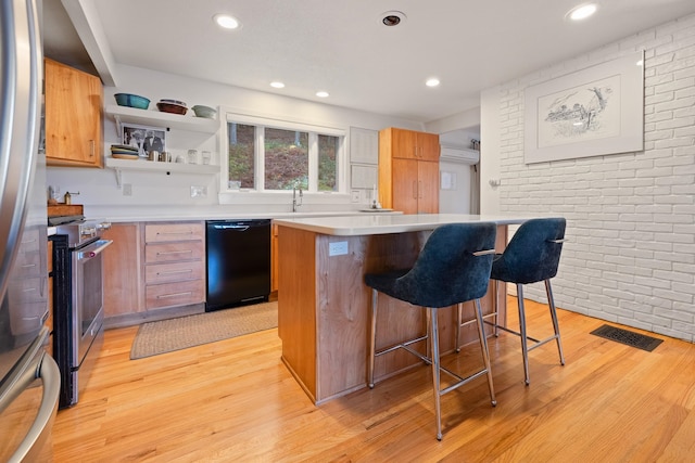 kitchen featuring a breakfast bar, a center island, light wood-type flooring, and appliances with stainless steel finishes