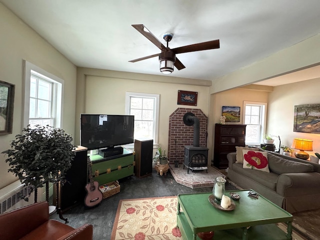 living room with a wood stove, ceiling fan, and radiator