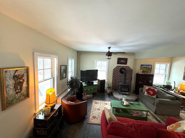 living room featuring hardwood / wood-style flooring, a wood stove, plenty of natural light, and ceiling fan