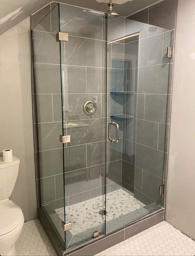 bathroom with tile patterned floors, toilet, and a shower with shower door