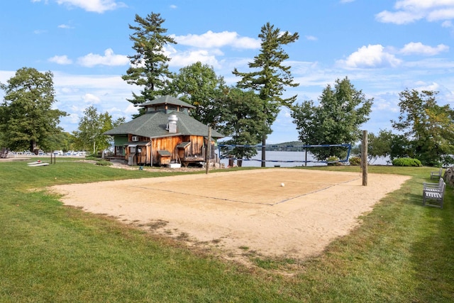 surrounding community with a lawn, a water view, and volleyball court