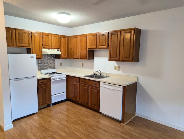 kitchen featuring sink, tasteful backsplash, a textured ceiling, white appliances, and light hardwood / wood-style floors