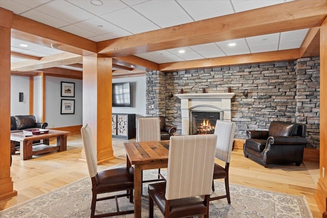 dining space with beam ceiling, a paneled ceiling, and light hardwood / wood-style flooring