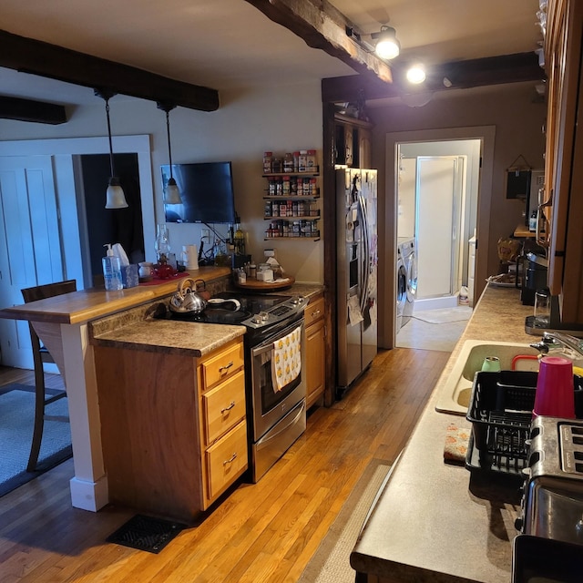 kitchen featuring hardwood / wood-style floors, a breakfast bar, hanging light fixtures, separate washer and dryer, and appliances with stainless steel finishes