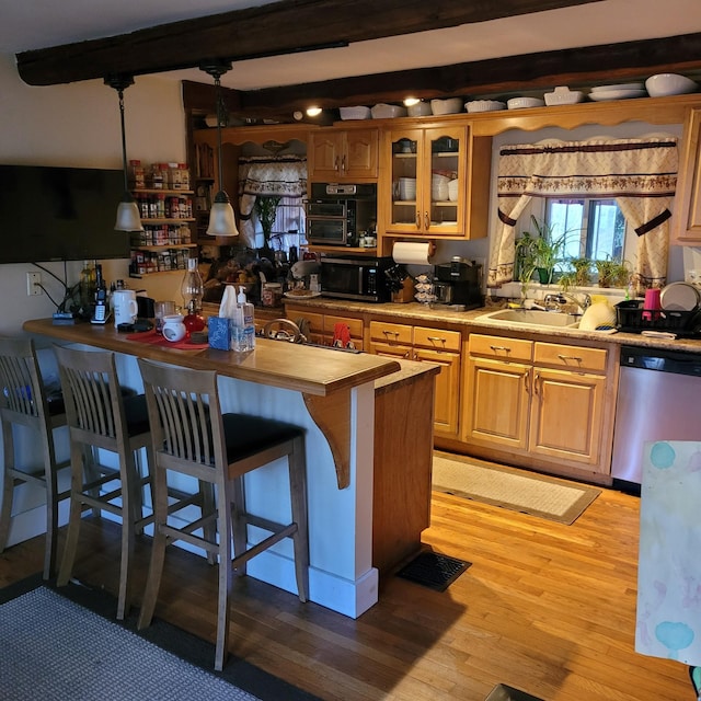 kitchen with sink, beamed ceiling, pendant lighting, appliances with stainless steel finishes, and light wood-type flooring