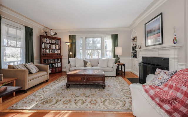 living room featuring crown molding, built in features, and light hardwood / wood-style floors