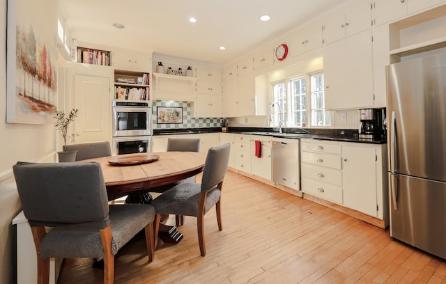 kitchen featuring white cabinetry, stainless steel appliances, sink, and light hardwood / wood-style flooring