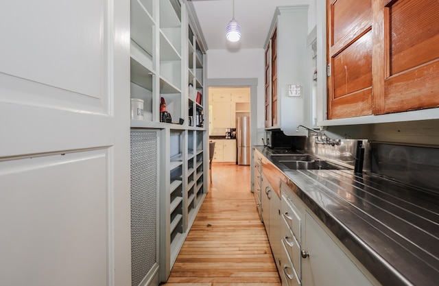 interior space with stainless steel fridge, decorative light fixtures, light hardwood / wood-style flooring, and white cabinets