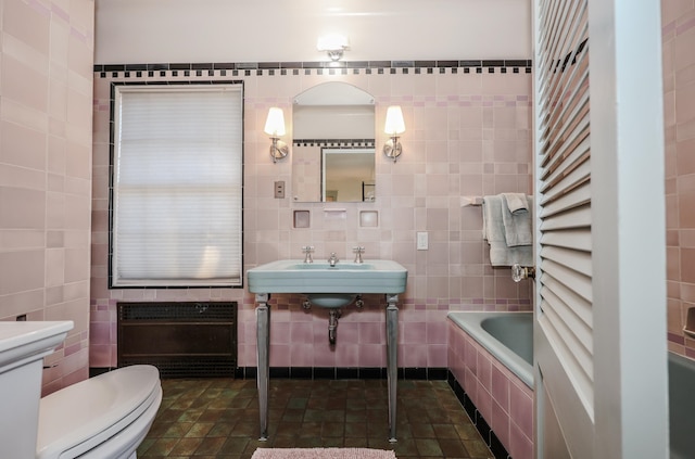 bathroom featuring toilet, tile patterned floors, a bath, and tile walls