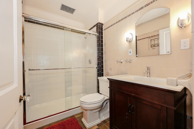 bathroom with tile walls, an enclosed shower, vanity, and toilet