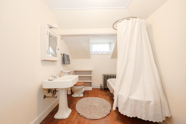 bathroom featuring radiator heating unit, toilet, hardwood / wood-style floors, and a tub