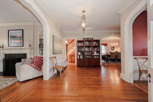 living area with ornamental molding, hardwood / wood-style floors, and built in shelves