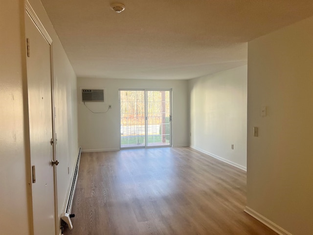 empty room featuring an AC wall unit, hardwood / wood-style floors, and a baseboard radiator