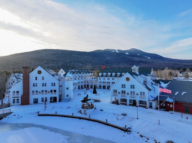 snowy aerial view featuring a mountain view and a residential view