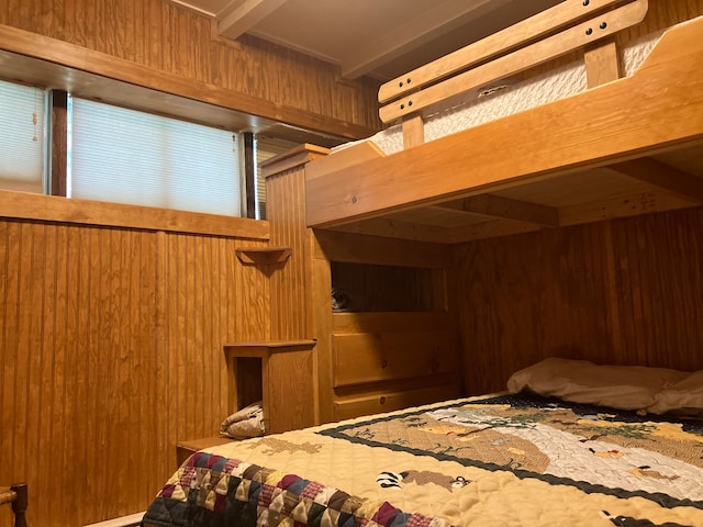 bedroom featuring wood walls and beam ceiling