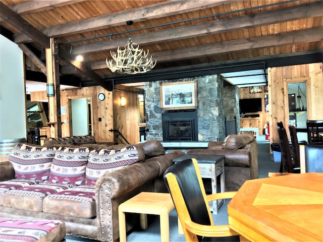 living room featuring beam ceiling, a stone fireplace, wood walls, and wood ceiling