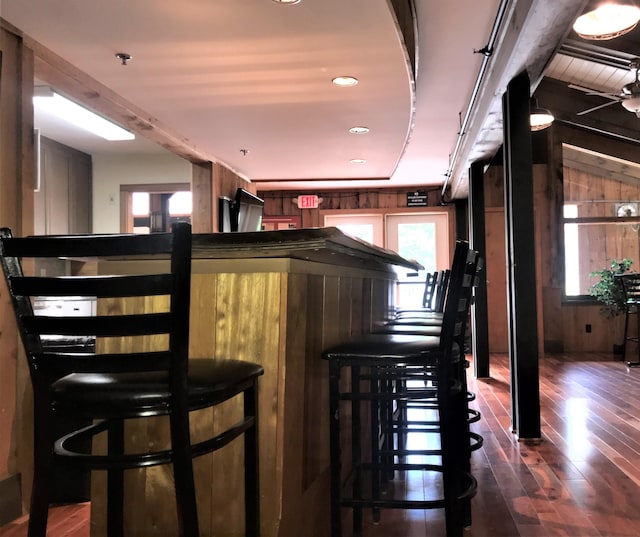 bar with dark hardwood / wood-style floors and wooden walls