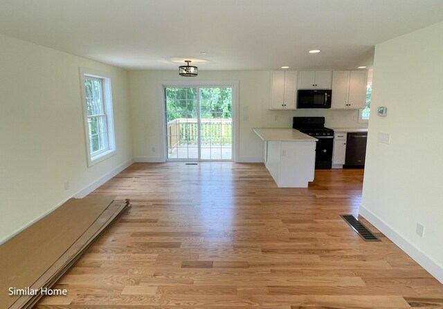 kitchen featuring white cabinetry, black appliances, and light hardwood / wood-style flooring