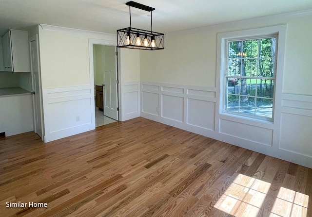 unfurnished dining area with an inviting chandelier and light hardwood / wood-style flooring